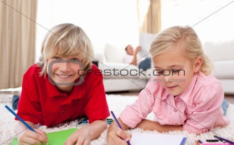 Adorable children drawing lying on the floor