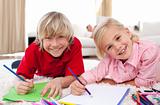 Smiling children drawing lying on the floor