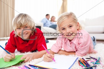 Lively siblings drawing lying on the floor