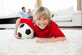 Smiling boy watching football match lying on the floor 