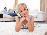 Cute little girl listening music lying on the floor in the living-room