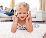 Cute little girl listening music lying on the floor 