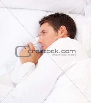 Portrait of a sad man lying in bed