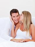 Intimate woman kissing her husband sitting on bed