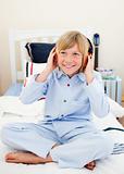 Smiling boy listening music sitting on bed