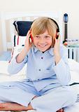 Positive boy listening music sitting on bed