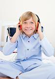 Laughing boy listening music sitting on bed