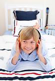 Relaxed boy listening music lying down on bed