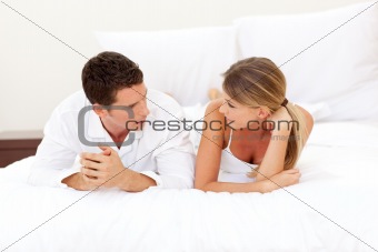 Young couple discussing lying on their bed