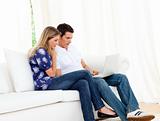 Romantic couple using a laptop sitting on sofa