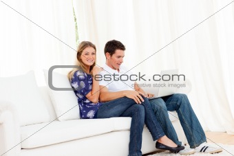 Jolly couple using a laptop sitting on sofa