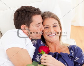 Portrait of a charming man kissing his wife lying on sofa