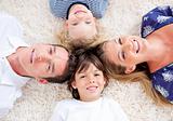 Smiling young family lying on the floor with heads together