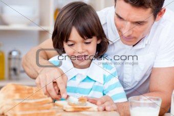 Loving father and his son spreading jam on bread