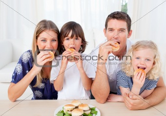 Hungry family eating burgers in the living room