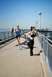 two females stretching on a pier 