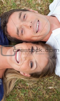 Smiling lovers lying on the grass 
