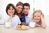 Children eating biscuits and dinking milk with their parents
