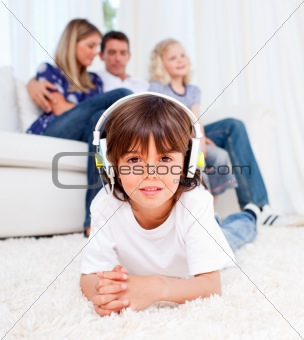 Cute little boy listening music lying on floor