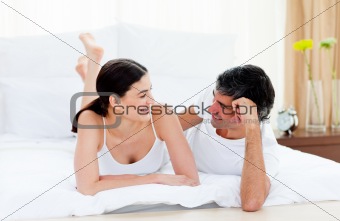 Affectionate couple interacting lying on their bed