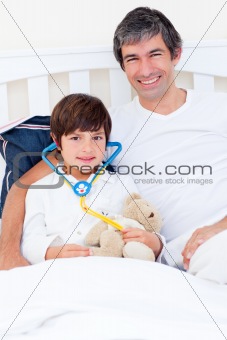 Smiling father and his sick son playing with a stethoscope