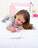 Concentrated Little girl writing on a notebook 