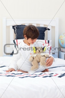 Cute little boy playing with a teddy bear 
