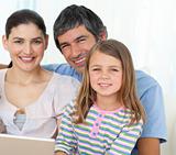 Little girl using a laptop with her parents 