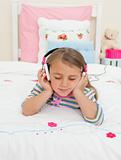 Beautiful Little gril listening to music lying on her bed