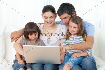 Jolly family using a laptop on the sofa