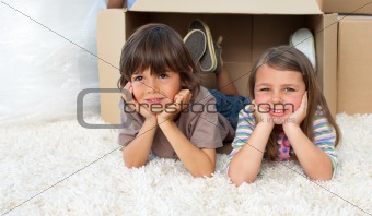 Brother and sister lying on floor in a new house