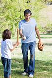 Adorable little boy playing baseball with his father