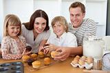 Smiling family eating muffins