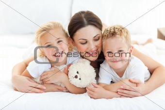 Cheerful children with their mother lying on a bed