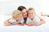 Cute children and their mom having fun lying on a bed 