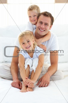 Cute blond boy hugging his dad sitting on a bed 