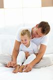 Charming father playing with his boy on a bed