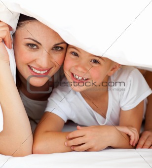 Cheerful mother and her little girl playing together on a bed 