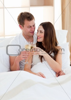 Intimate couple drinking champagne lying in bed