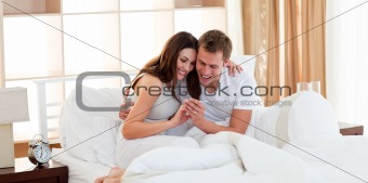 Attentive couple finding out results of a pregnancy test sitting on bed