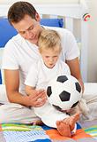 Blond little boy and his father playing with a soccer ball