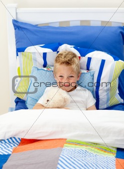 Adorable little boy lying in bed