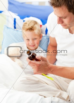 Charming father giving cough syrup to his sick son