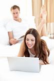 Woman using laptop lying on her bed