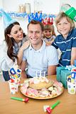 Elated man celebrating his birthday with his wife and his children in the kitchen