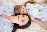 Cheerful mother and her daughter lying on the floor