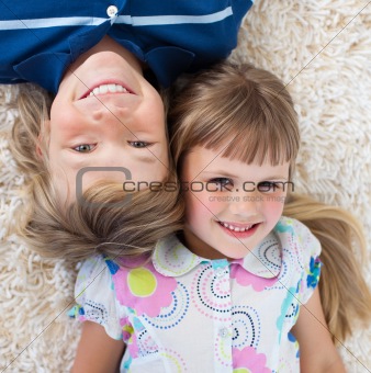 Adorable siblings lying on the floor with heads together