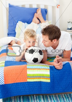 Adorable little boy and his father watching a football match 