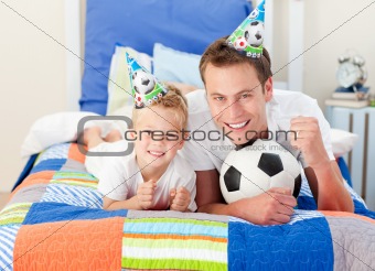 Cute little boy and his father watching a football match