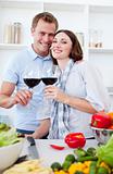 Smiling couple drinking wine while cooking 